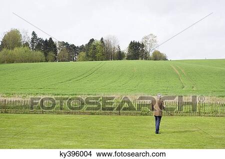 Man using a mobile phone in a field View Large Photo Image Picture - Man using a mobile phone in a field. Fotosearch