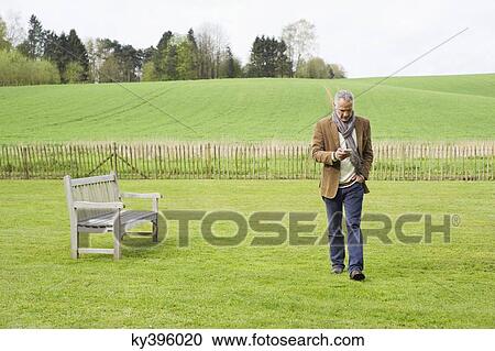 Man using a mobile phone in a field View Large Photo Image Stock Image - Man using a mobile phone in a field. Fotosearch