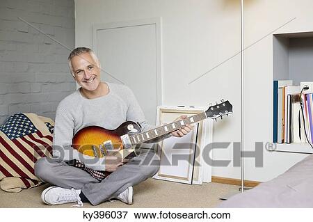 Portrait of a happy man playing a guitar View Large Photo Image Stock Photo - Portrait of a happy man playing a guitar. Fotosearch