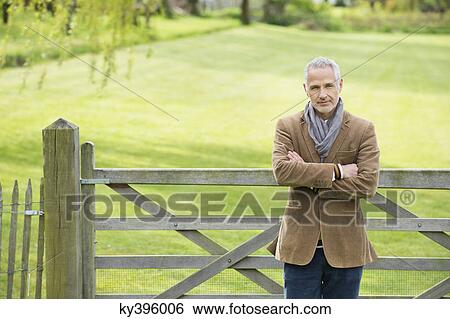 Portrait of a man standing in a park View Large Photo Image Stock Photograph - Portrait of a man standing in a park. Fotosearch
