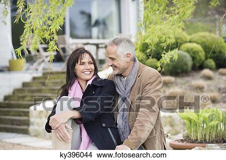 Picture - Romantic couple sitting in a garden and smiling. Fotosearch