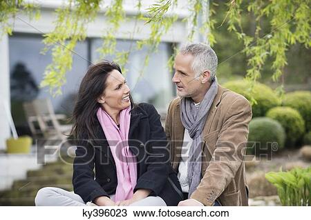 Stock Image - Romantic couple sitting in a garden and smiling. Fotosearch