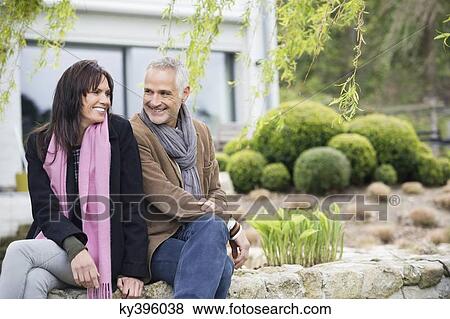 Romantic couple sitting in a garden and smiling View Large Photo Image Stock Photo - Romantic couple sitting in a garden and smiling. Fotosearch