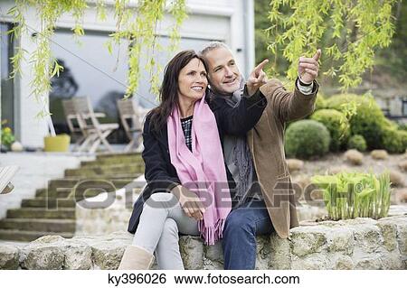 Stock Photograph - Romantic couple sitting in a garden. Fotosearch