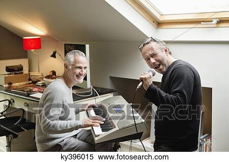 Stock Photography - Two male friends playing a piano and singing. Fotosearch