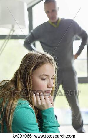 Girl looking upset with her father standing beside her View Large Photo Image Stock Photograph - Girl looking upset with her father standing beside her. Fotosearch