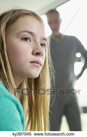 Girl looking upset with her father standing beside her View Large Photo Image Stock Photography - Girl looking upset with her father standing beside her. Fotosearch
