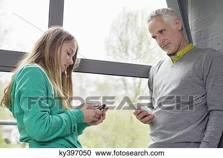 Man and daughter using their mobile phones View Large Photo Image Stock Image - Man and daughter using their mobile phones. Fotosearch