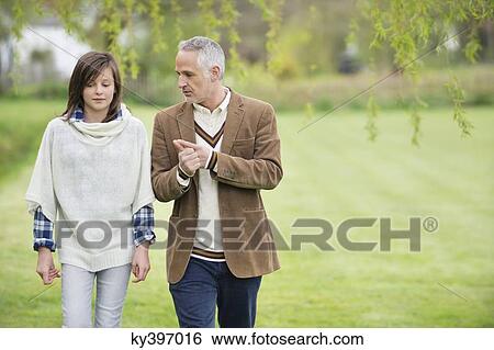 Stock Photograph - Man discussing with his daughter during walk in a park. Fotosearch