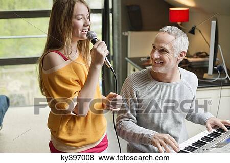 Man playing a piano with his daughter singing View Large Photo Image Stock Photo - Man playing a piano with his daughter singing. Fotosearch