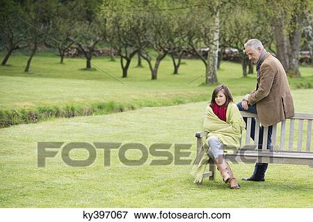 Man sitting with his daughter on a bench in a park View Large Photo Image Stock Photo - Man sitting with his daughter on a bench in a park. Fotosearch