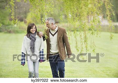 Man walking with his daughter in a park View Large Photo Image Stock Image - Man walking with his daughter in a park. Fotosearch