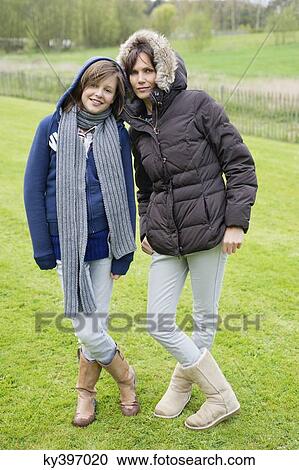 Stock Image - Woman with her daughter standing in a field. Fotosearch