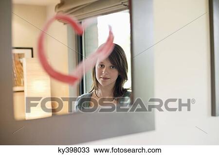 Girl looking at reflection in mirror decorated with heart shape View Large Photo Image Stock Image - Girl looking at reflection in mirror decorated with heart shape. Fotosearch