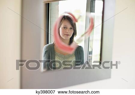 Girl looking at reflection in mirror decorated with heart shape View Large Photo Image Stock Photo - Girl looking at reflection in mirror decorated with heart shape. Fotosearch