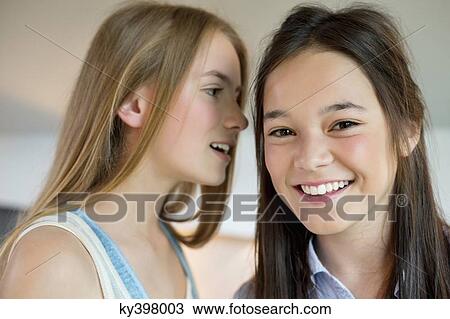 Girl whispering to her friend View Large Photo Image Stock Image - Girl whispering to her friend. Fotosearch