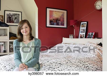 Stock Photo - Portrait of a girl sitting on the bed and smiling. Fotosearch