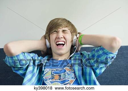 Stock Photo - Teenage boy listening to music and looking excited. Fotosearch