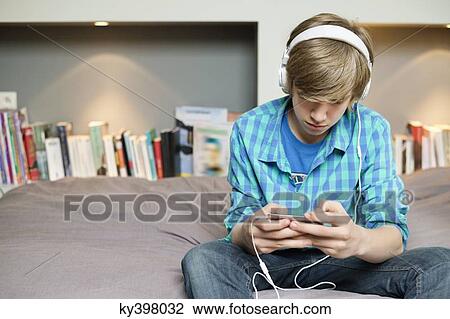 Teenage boy listening to music on iPod at home View Large Photo Image Stock Image - Teenage boy listening to music on iPod at home. Fotosearch