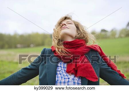 Stock Photo - Beautiful woman daydreaming in a field. Fotosearch