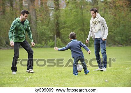 Boy playing soccer with two men in a park View Large Photo Image Stock Photo - Boy playing soccer with two men in a park. Fotosearch