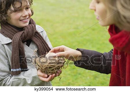 Boy showing a bird's nest to his mother View Large Photo Image Picture - Boy showing a bird's nest to his mother. Fotosearch