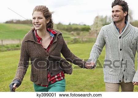 Couple holding hands in a field View Large Photo Image Stock Image - Couple holding hands in a field. Fotosearch