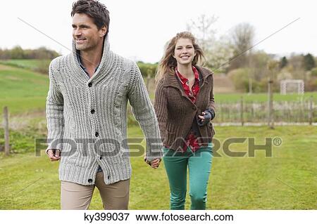 Couple holding hands in a field View Large Photo Image Stock Photo - Couple holding hands in a field. Fotosearch