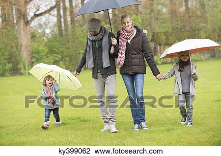 Family walking with umbrellas in a park View Large Photo Image Stock Image - Family walking with umbrellas in a park. Fotosearch