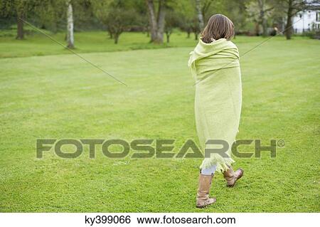 Girl wrapped in a blanket and walking in a field View Large Photo Image Stock Photograph - Girl wrapped in a blanket and walking in a field. Fotosearch