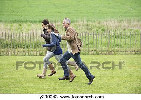Happy family running in a field View Large Photo Image Stock Image - Happy family running in a field. Fotosearch