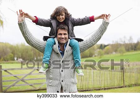 Man carrying his son on shoulders View Large Photo Image Stock Image - Man carrying his son on shoulders. Fotosearch
