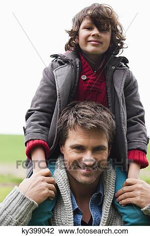 Stock Image - Man carrying his son on shoulders. Fotosearch