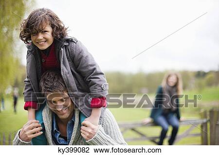 Man carrying his son on shoulders View Large Photo Image Stock Image - Man carrying his son on shoulders. Fotosearch
