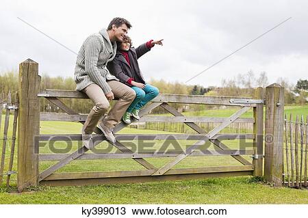 Man sitting with his son on the gate of a cottage View Large Photo Image Stock Image - Man sitting with his son on the gate of a cottage. Fotosearch
