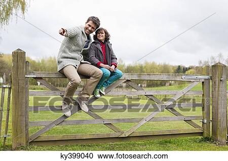 Man sitting with his son on the gate of a cottage View Large Photo Image Stock Image - Man sitting with his son on the gate of a cottage. Fotosearch