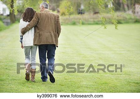 Stock Photograph - Man walking with his daughter in a park. Fotosearch