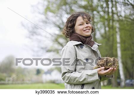Stock Photography - Portrait of a boy holding a bird's nest in a park. Fotosearch
