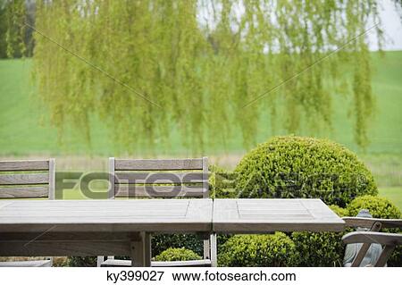 Table with chairs in a garden View Large Photo Image Stock Photo - Table with chairs in a garden. Fotosearch