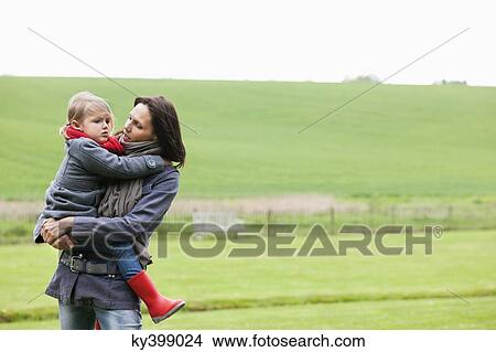 Woman carrying her daughter in a field View Large Photo Image Picture - Woman carrying her daughter in a field. Fotosearch