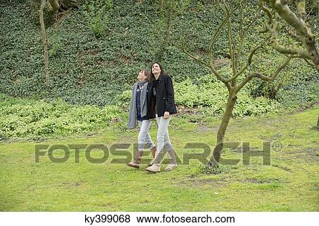 Woman with her daughter walking in an orchard View Large Photo Image Stock Photo - Woman with her daughter walking in an orchard. Fotosearch