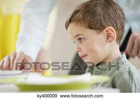 Boy sitting at a dining table View Large Photo Image Stock Photo - Boy sitting at a dining table. Fotosearch