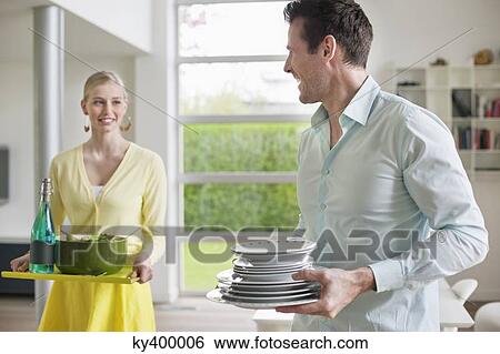 Couple carrying food and plates for serving View Large Photo Image Stock Photograph - Couple carrying food and plates for serving. Fotosearch