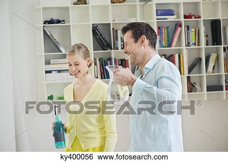 Couple holding a pitcher and a bottle View Large Photo Image Stock Photograph - Couple holding a pitcher and a bottle. Fotosearch