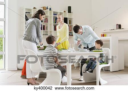 Stock Image - Family at dining table with guests. Fotosearch