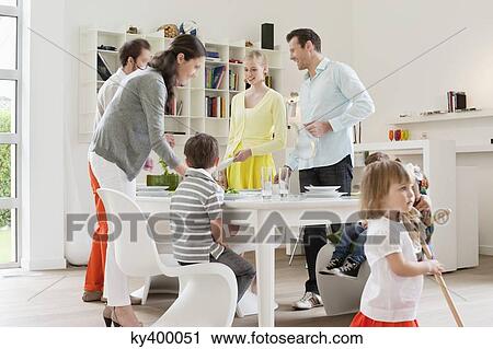 Stock Image - Family at dining table with guests. Fotosearch