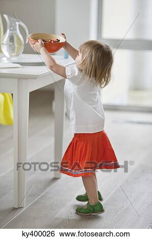 Girl setting bowl of food on a table View Large Photo Image Stock Photograph - Girl setting bowl of food on a table. Fotosearch