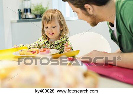 Stock Photo - Man and daughter at breakfast table. Fotosearch