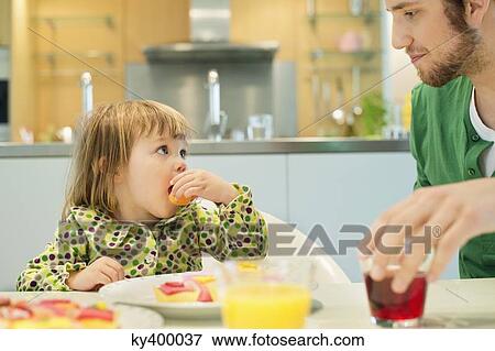 Stock Photo - Man and daughter at breakfast table. Fotosearch