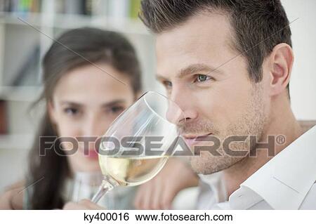 Man drinking white wine with his wife in the background View Large Photo Image Stock Photograph - Man drinking white wine with his wife in the background. Fotosearch